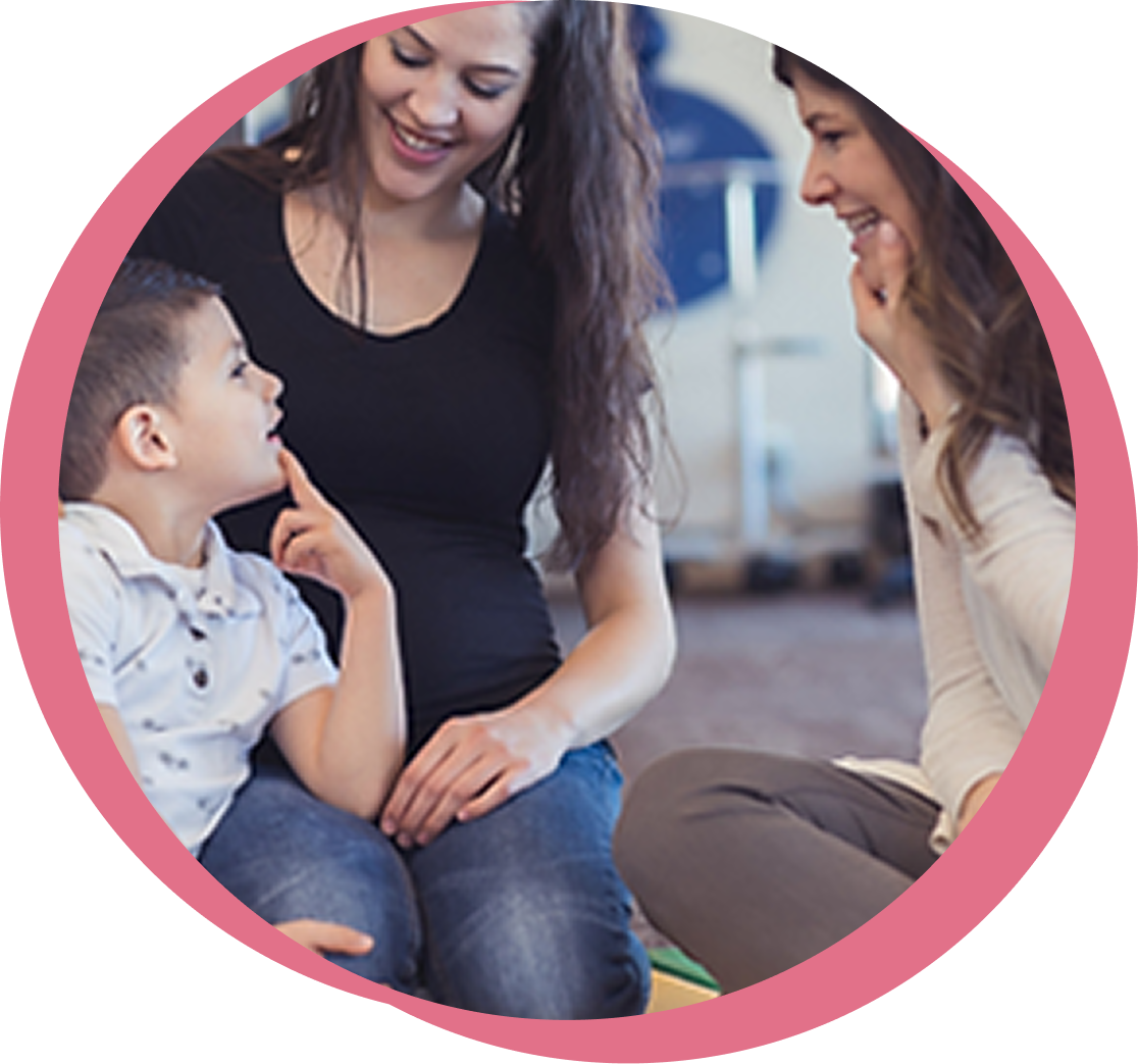A clinician and caregiver smiling with a young child during an autism screening visit