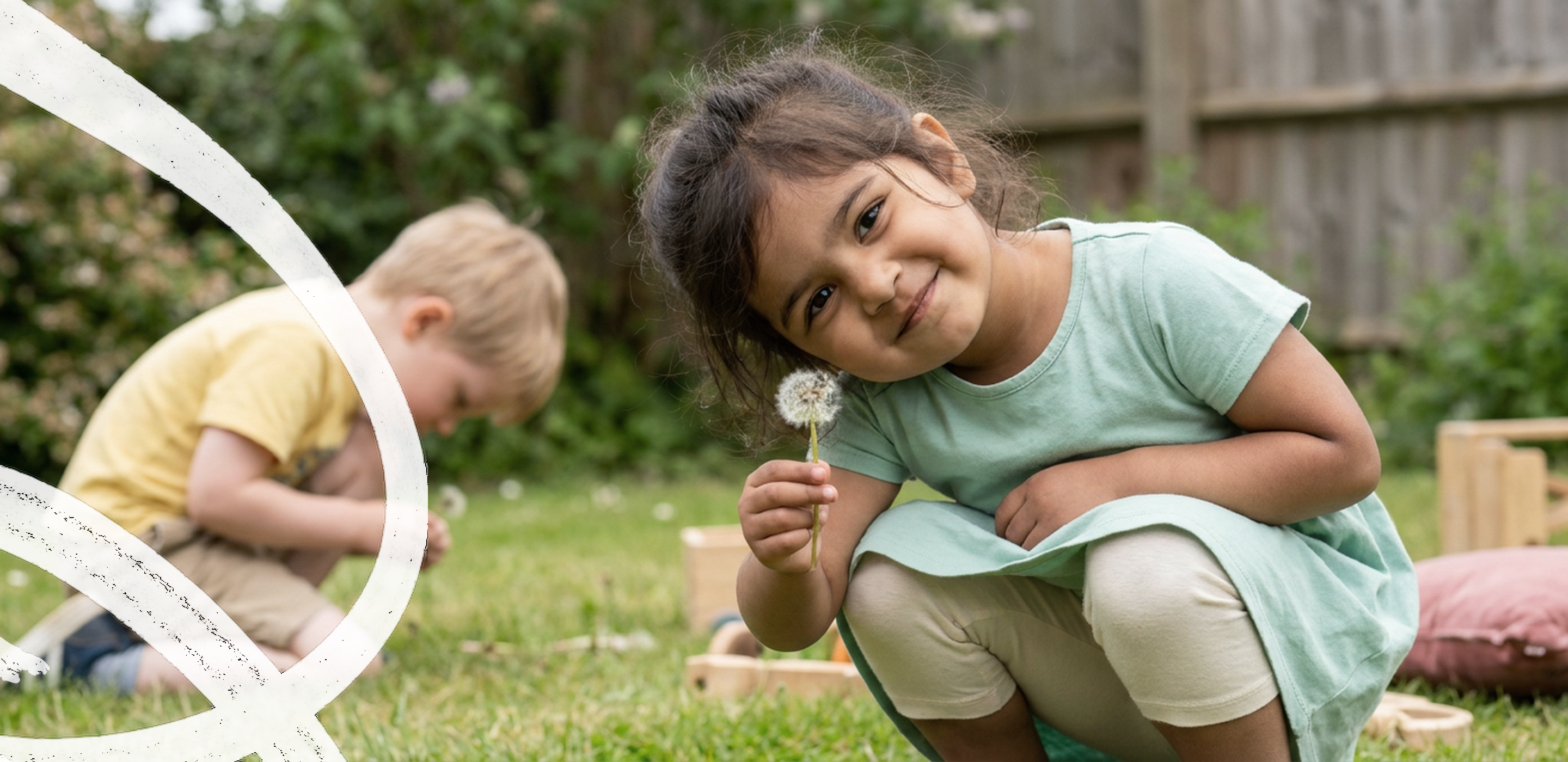 Two young girls smiling and playing together on the grass at ANNA